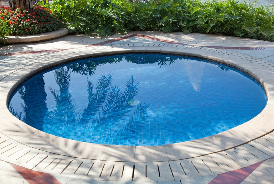 Piscine circulaire extérieure avec margelles en pierre naturelle et joints décoratifs