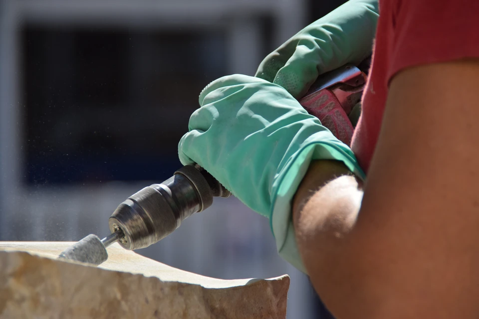Scène extérieure d'atelier de maçonnerie avec outils de taille de pierre disposés sur blocs calcaires bruts